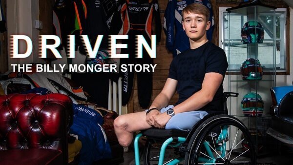 Billy Monger in a wheelchair surrounded by racecar driving memorabilia
